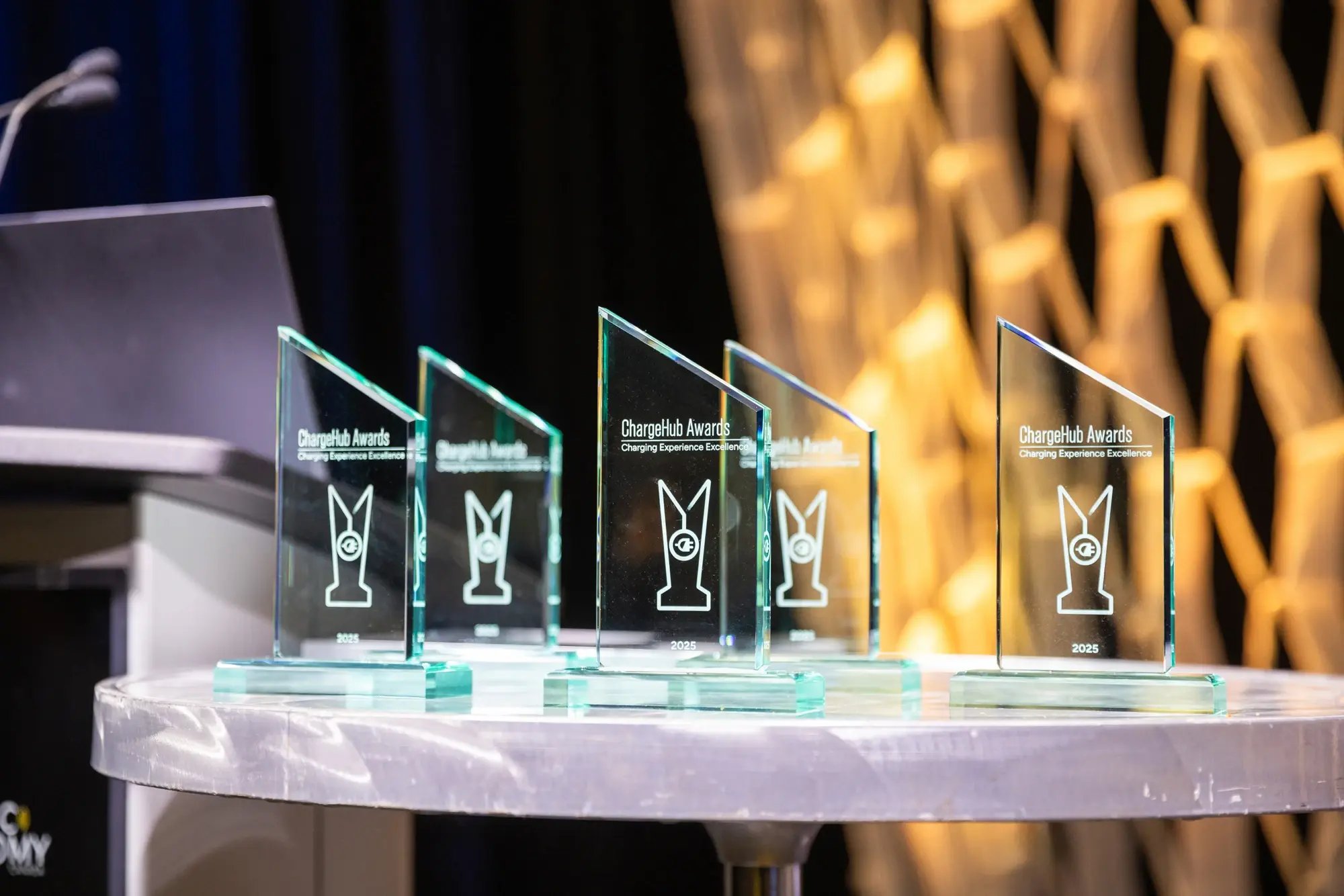 Glass ChargeHub Awards trophies displayed on a table beside the podium before the ceremony.