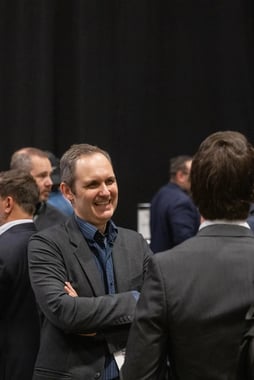 Simon Ouellette smiling while chatting with attendees at an EV charging industry event.