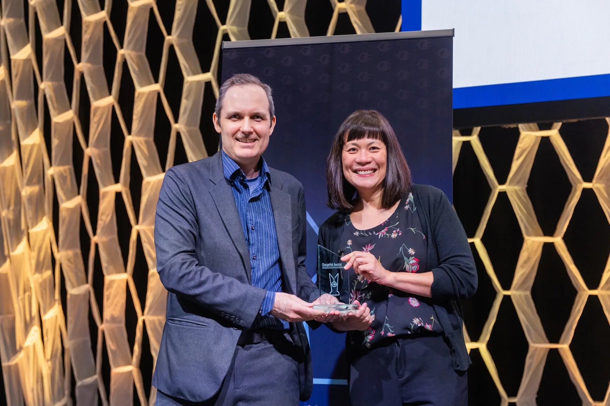 Simon Ouellette and an award recipient holding a ChargeHub Awards trophy on stage.