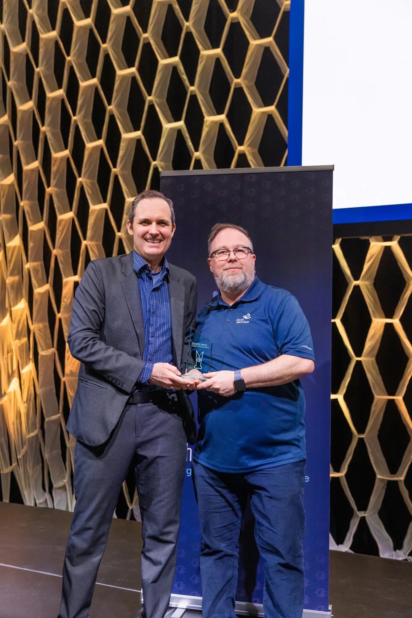 Simon Ouellette and an award recipient holding a ChargeHub Awards trophy during the ceremony.