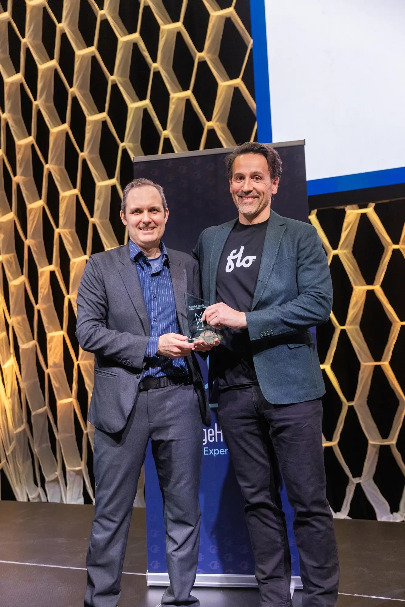 Simon Ouellette and a FLO representative posing with a ChargeHub Awards trophy at the ceremony.