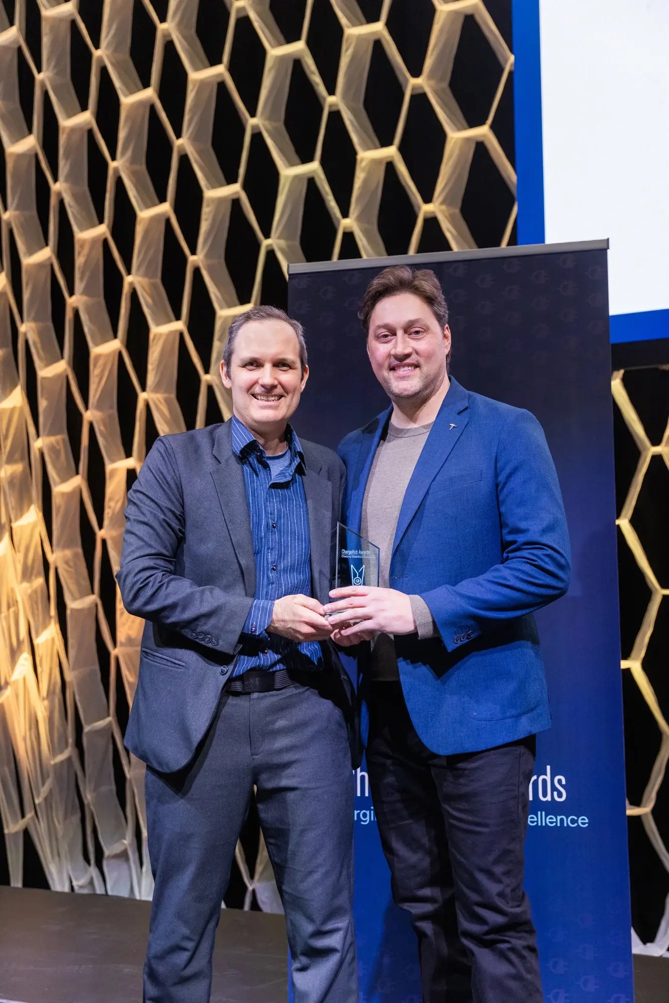 Simon Ouellette and a Tesla representative holding a ChargeHub Awards trophy during the ceremony.