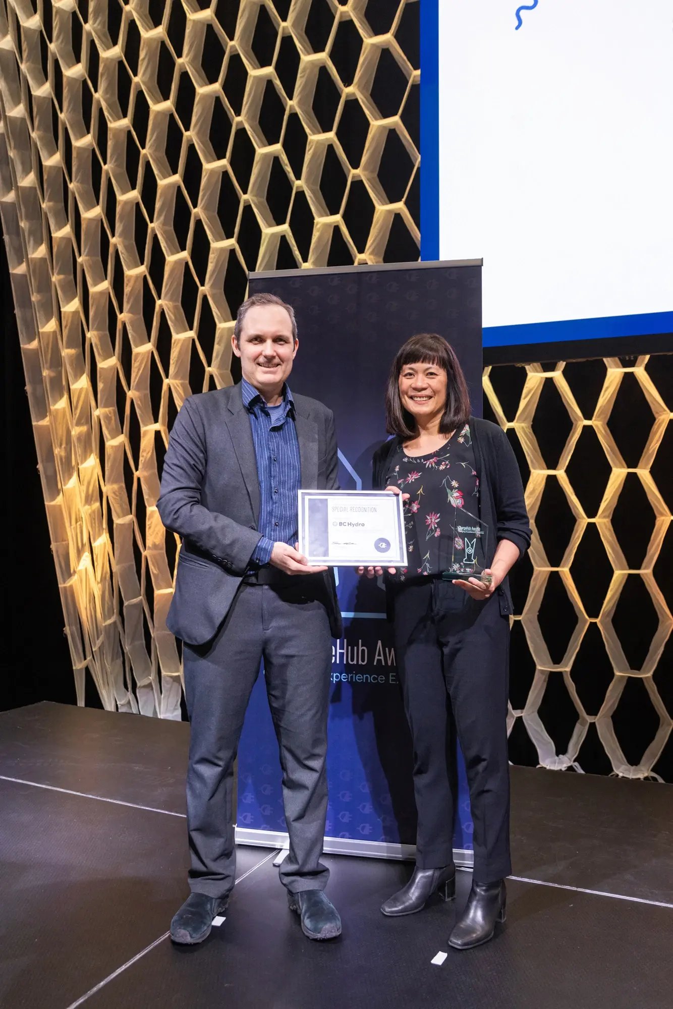 Simon Ouellette and a BC Hydro recipient posing with a special recognition certificate and ChargeHub Awards trophy.