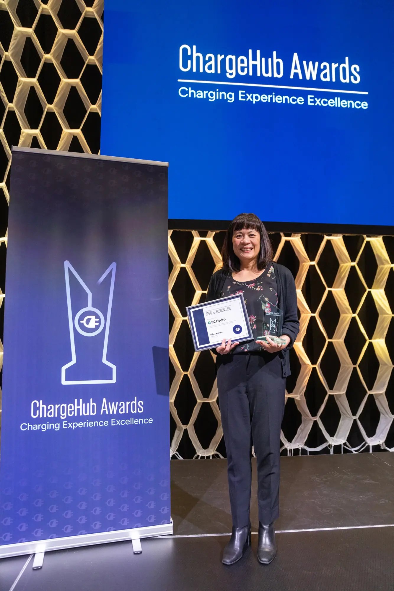 BC Hydro special recognition recipient posing with a certificate and ChargeHub Awards trophy on stage.