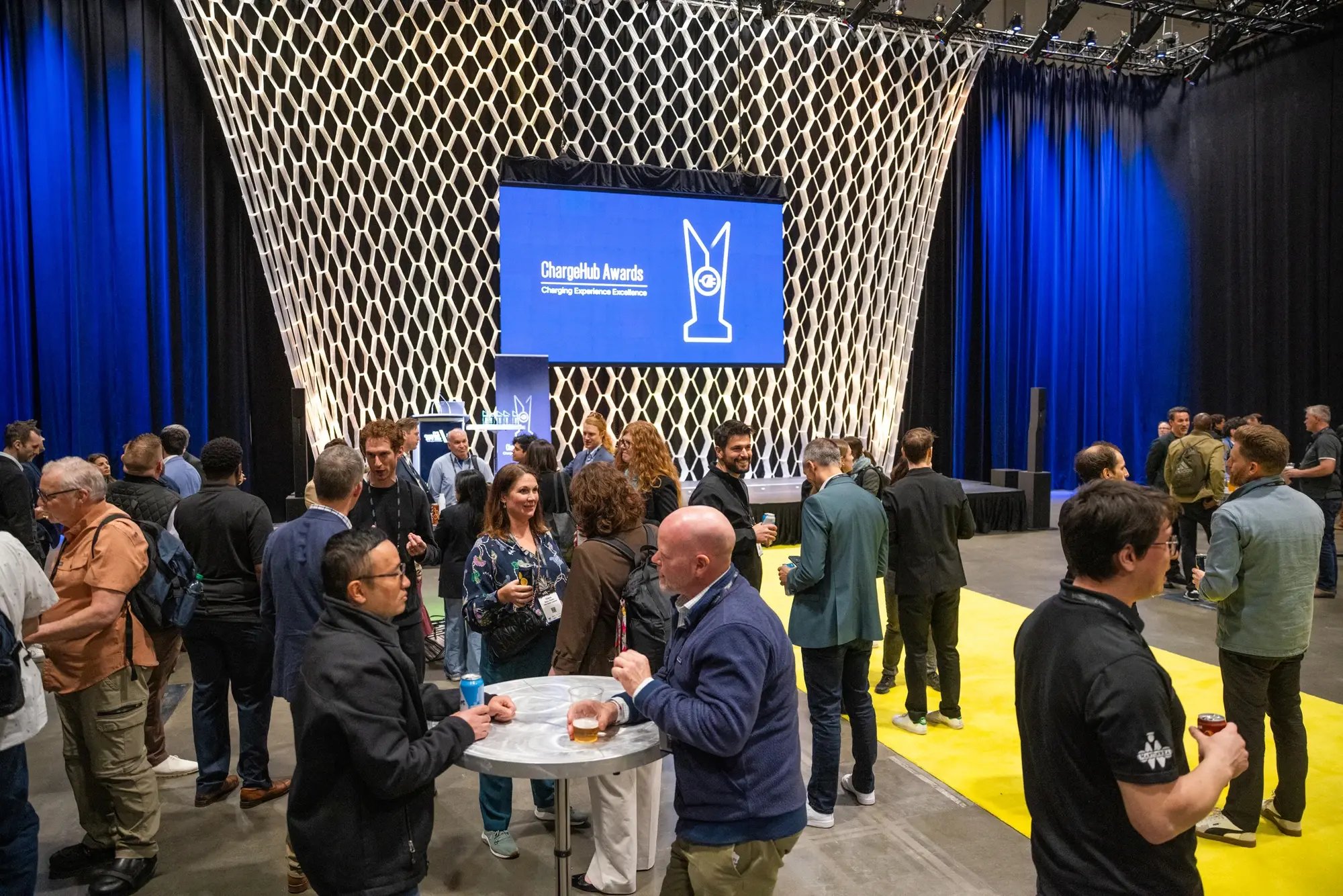 Wide view of attendees networking in front of the ChargeHub Awards stage.