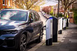 Electric vehicle being charged at a row of public charging stations in a parking lot