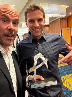 Two men take a selfie with the Accolades 2026 Gala trophy.