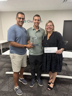 Three people hold the Innovation and Technology trophy in ChargeHub's office.