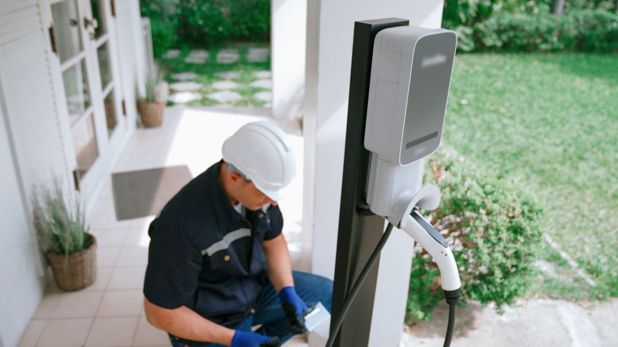 Technicien installant une borne de recharge pour voiture électrique à domicile