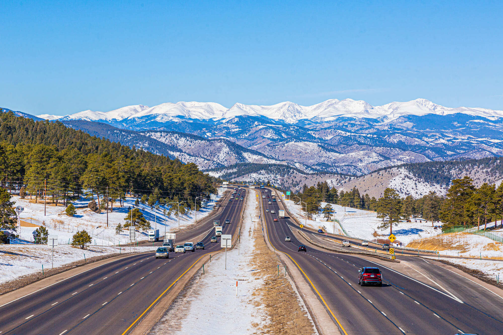 Road winding through a snowy mountain landscape in winter, illustrating a winter getaway by electric vehicle.