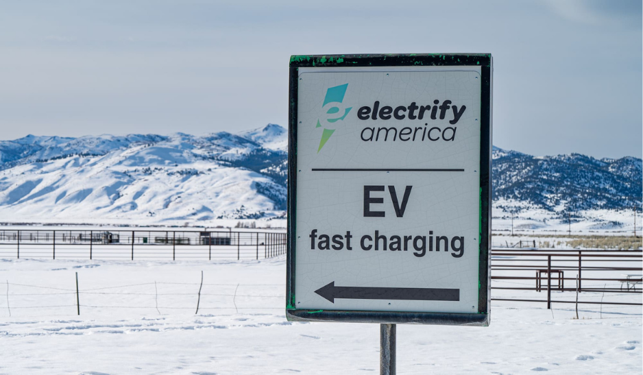 Panneau indiquant une station de recharge rapide pour véhicules électriques dans un paysage enneigé.